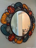 Full view of round mirror showing multicolor frame and reflective surface