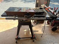 Full view of Sears Craftsman table saw on stand with accessories on tabletop