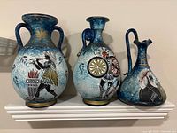 Front view of three ceramic vases showing mythological scenes and blue crackle glaze