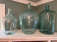 Front view of all three demijohn bottles showing size and color