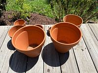 All eight terracotta items on wooden deck, showing scale and color