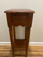 Front view of wooden side table showing drawer and shelf