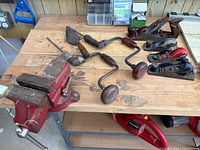 All nine tools laid out on workbench: vise, brace drills, hand planes, saw, trowel