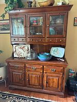 Full view of wooden hutch showing upper glass cabinet and lower sideboard