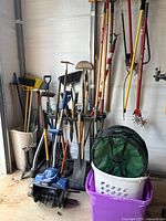 Overall view of assorted long-handle tools, Snow Joe electric snow shovel, collapsible container and organizer rack