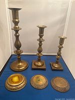 Front view of three brass candlesticks and three coasters