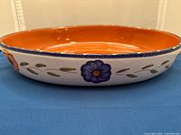 Side view of oval dish showing exterior floral design and orange interior