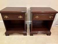 Front view of both nightstands showing drawer, open shelf, brass pulls, finish