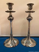 Front view of both ornate silver-plated candlesticks