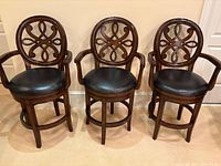 Front view of three matching wooden swivel bar stools