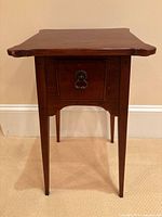 Front view of hardwood side table showing drawer, pull, tapered legs