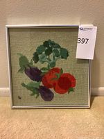 Full view of framed embroidery showing vegetable design and frame