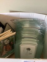 Box containing multiple clear glass clip frames and additional frames