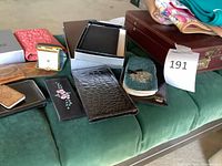group view of briefcase, travel clock, wallets, eyeglass case on green surface