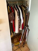 Closet with hanging clothes, walker, projector screen stand, hat, flashlight, binocular case