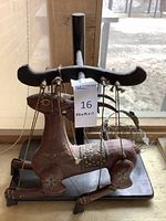 Wooden animal marionette on stand with strings and metal bowl behind