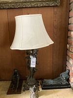 Overall lot view showing metal cherub lamp, seated man sculpture, reclining man sculpture