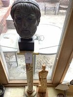 Full view bust on pedestal with wooden figure at base
