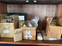 Multiple cardboard boxes and small packages holding assorted pins and brooches