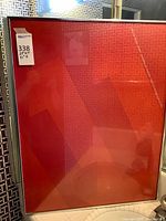 Full view of framed poster showing red/orange design and frame