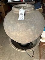 Overall view showing urn vessel atop basin with power cord visible
