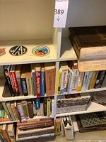 Shelf containing numerous books, VHS box set, loose tapes and embroidered patches