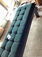 Top angled view of emerald green velvet bench showing tufted upholstery and leg style