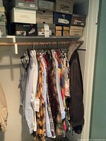 Wide closet view showing hanging shirts, leather jacket and boxed shoes