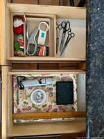 Overview of drawer contents showing scissors, hand punch, matchboxes, Christmas ornaments, flashlight, ruler, magnifying glass, dish