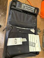Open carrying case showing handset, cables, manual