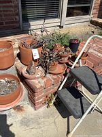 Group of terra-cotta pots on brick step with folding step stool