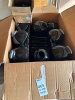 Open carton showing multiple black lamp shades and stacked clamp bases