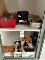 Shelf with red box of brushes, zip shoe shine kit, plastic bin with polish tins, large brush