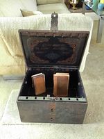 Open metal chest showing interior painting and two books