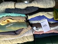Stack of folded sweaters and pants with lot tag visible