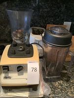 Vitamix blender base, blending jar, toaster, decorative jar with stones visible on countertop