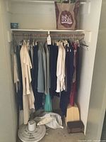 Closet with hanging women’s garments, pedestal fan base visible