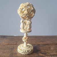 Full view of carved puzzle ball on stand