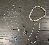 All six necklaces laid out on black surface
