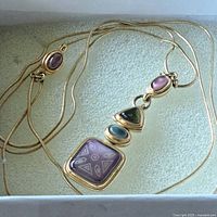 Full view of gold-tone snake chain necklace and multistone geometric pendant in box