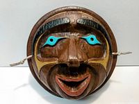 Front view of carved wooden mask showing colours, carving detail, and hanging strings