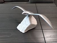 Full view of aluminum seagull sculpture on stone base