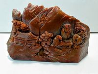 Front view of reddish brown jade sculpture showing landscape scene