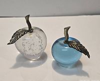 Clear and blue glass apple paperweights with metal leaves