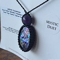 Front view of pendant showing amethyst cabochon, abalone shell and macramé cord