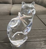 Full view of clear crystal cat figurine with ribbon, on table