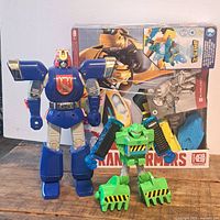 Blue and green Transformer figures in front of boxed Transformer set