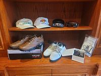 Front view of golf hats, sunglasses, and golf shoes on wood shelf