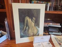 Framed nude artwork with two Franklin Mint coins and authentication certificate on desk