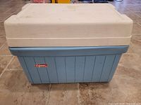 Front angle showing cooler with white lid, blue body, and Coleman logo